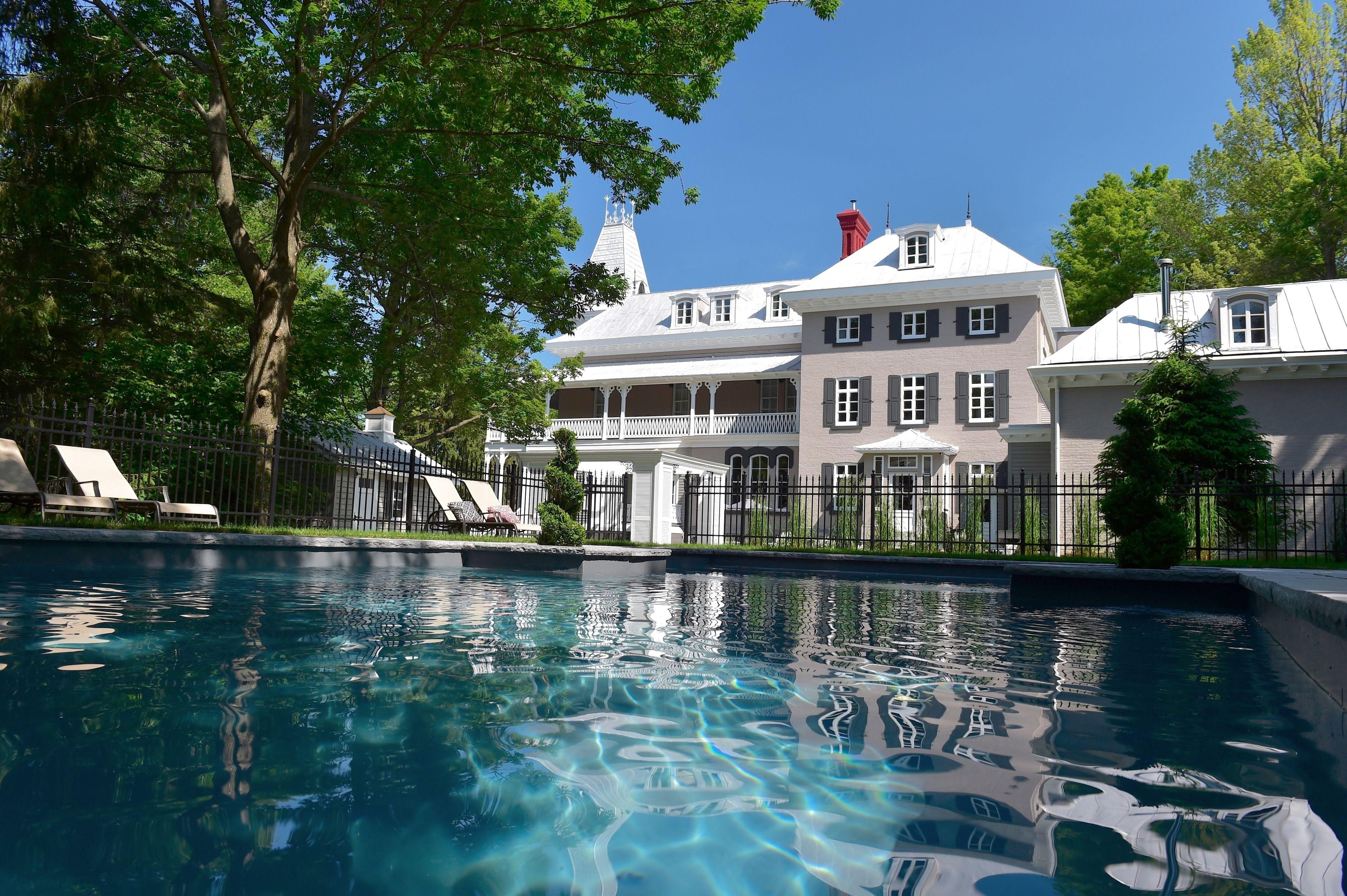 Manoir Maplewood with swimming pool surrounded by lush greenery